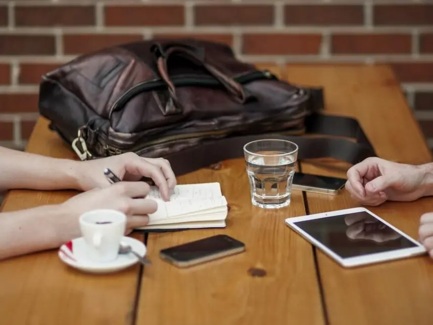 Un incontro di lavoro attorno a un tavolo, con appunti e un tablet
